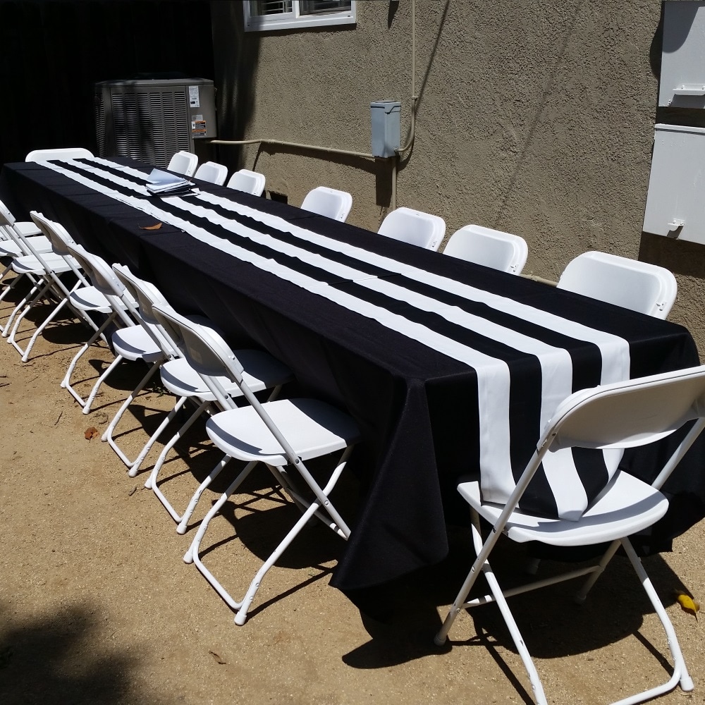 Rectangular Banquet tables with black tablecloths and white folding chairs for rent from Big Blue Sky Party Rentals